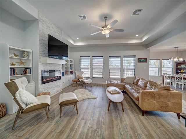 living room with a ceiling fan, wood finished floors, healthy amount of natural light, a stone fireplace, and recessed lighting