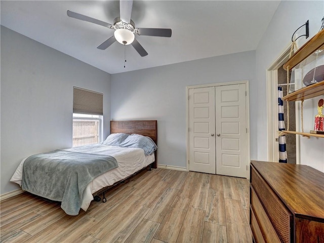 bedroom featuring wood finished floors, a closet, baseboards, and a ceiling fan