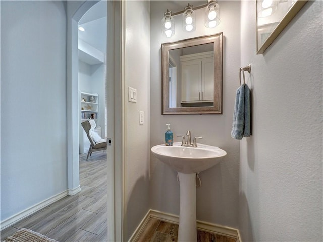 bathroom with wood finished floors, baseboards, and a sink
