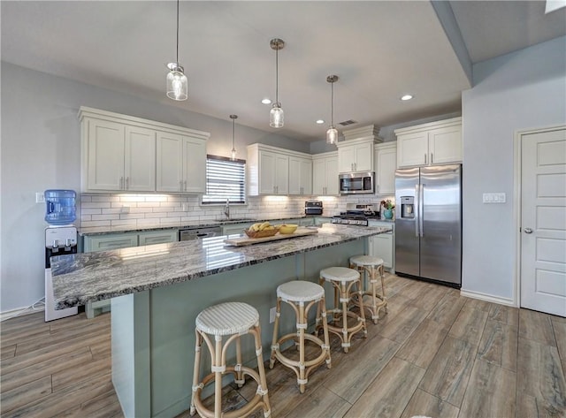 kitchen with stainless steel appliances, light wood-style floors, a center island, decorative backsplash, and white cabinetry