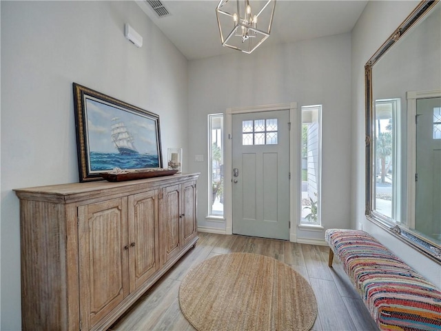 foyer featuring a chandelier, healthy amount of natural light, and light wood-style flooring