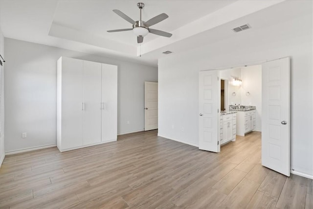15101 Tesoro Dr, Corpus Christi, TX 78418 - unfurnished bedroom featuring a tray ceiling, light wood-type flooring, ensuite bath, and a ceiling fan