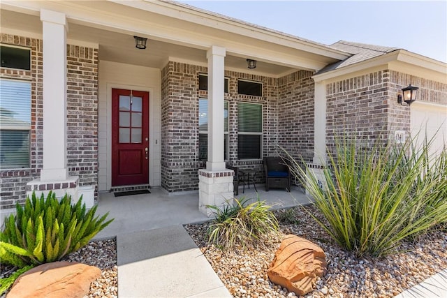 view of exterior entry featuring brick siding, covered porch, and an attached garage