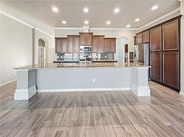 kitchen featuring light hardwood / wood-style floors, light stone counters, a spacious island, and appliances with stainless steel finishes