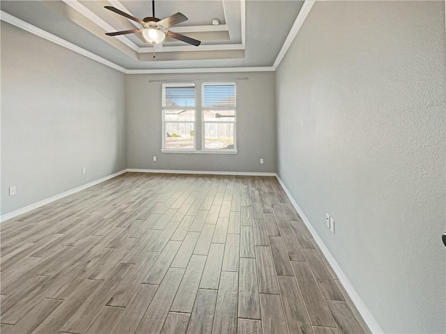 spare room with a raised ceiling, light hardwood / wood-style flooring, ceiling fan, and crown molding