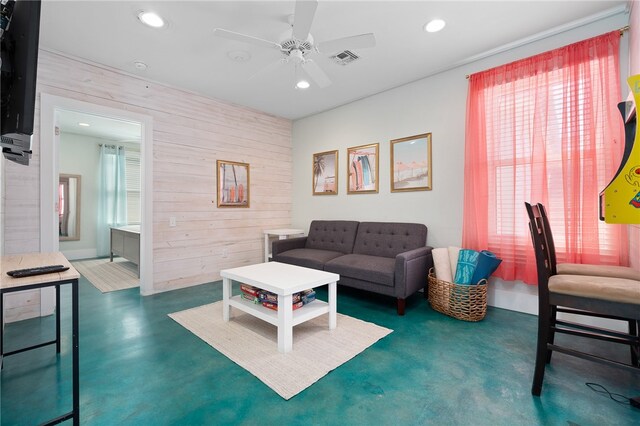 living room with plenty of natural light, wood walls, and ceiling fan