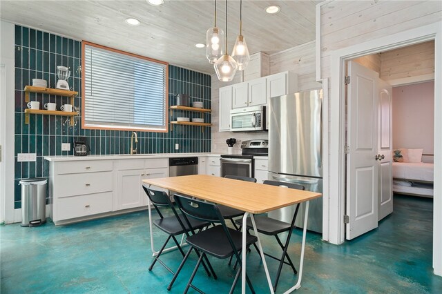 kitchen with sink, appliances with stainless steel finishes, white cabinets, pendant lighting, and decorative backsplash