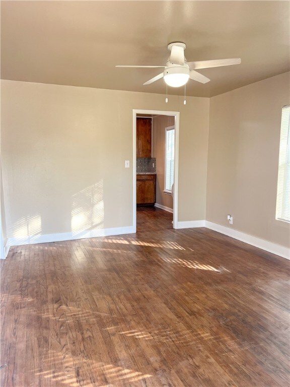 unfurnished room with dark wood-type flooring and ceiling fan