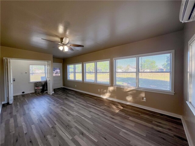 unfurnished living room featuring dark wood-type flooring, an AC wall unit, and ceiling fan