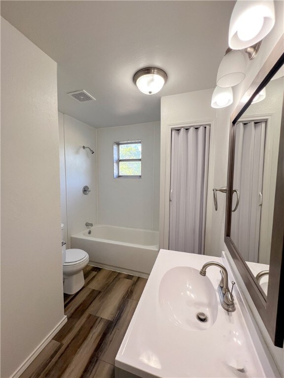 full bathroom with vanity, wood-type flooring, toilet, and  shower combination