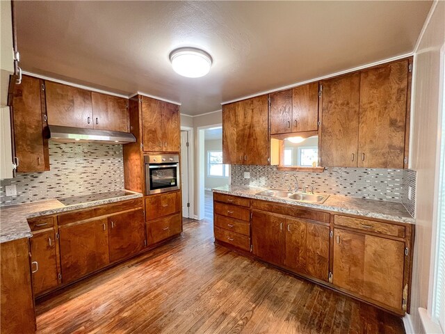 kitchen with black electric cooktop, sink, extractor fan, light hardwood / wood-style flooring, and stainless steel oven