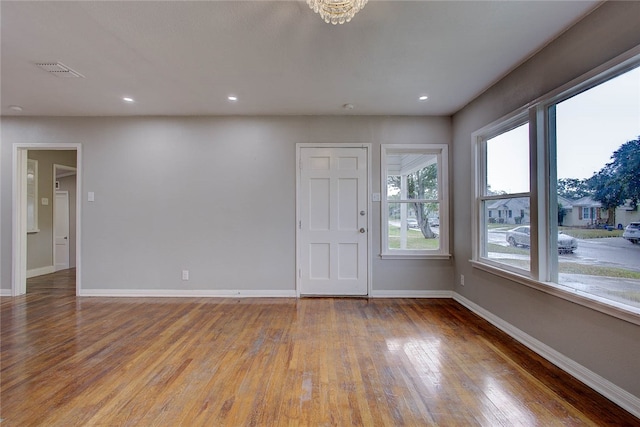 spare room with wood-type flooring and an inviting chandelier