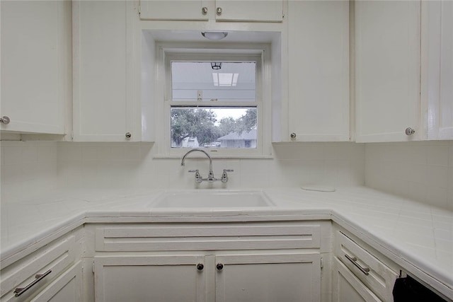 kitchen featuring white cabinets, decorative backsplash, and sink