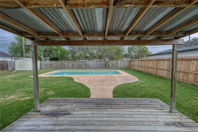 view of swimming pool featuring a yard, a deck, and a shed