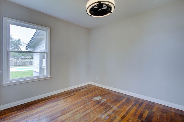 empty room with plenty of natural light, wood-type flooring, and vaulted ceiling