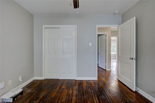 unfurnished bedroom with ceiling fan, a closet, and dark wood-type flooring