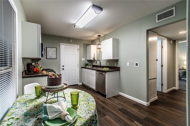 950 Susan Dr, Corpus Christi, TX 78412 - kitchen with dark countertops, stainless steel dishwasher, a sink, dark wood finished floors, and white cabinetry