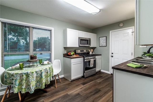 950 Susan Dr, Corpus Christi, TX 78412 - kitchen featuring appliances with stainless steel finishes, a sink, dark wood-style flooring, white cabinets, and baseboards