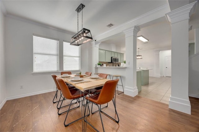 dining room featuring ornamental molding, ornate columns, and light hardwood / wood-style flooring