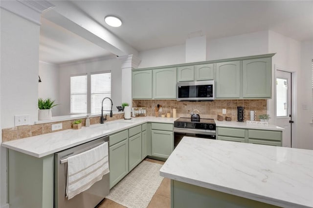 kitchen with green cabinetry, sink, kitchen peninsula, backsplash, and stainless steel appliances