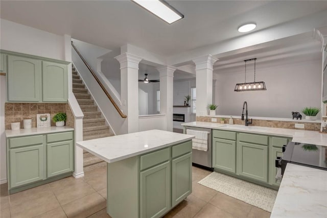 kitchen with ornate columns, green cabinetry, stainless steel dishwasher, sink, and pendant lighting