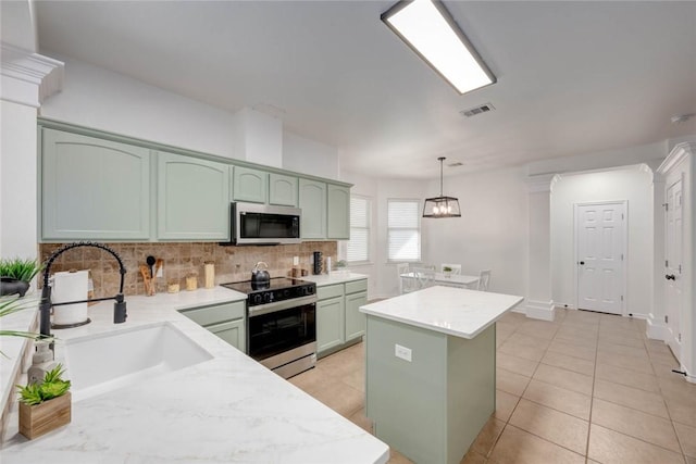 kitchen featuring pendant lighting, appliances with stainless steel finishes, sink, green cabinetry, and a kitchen island