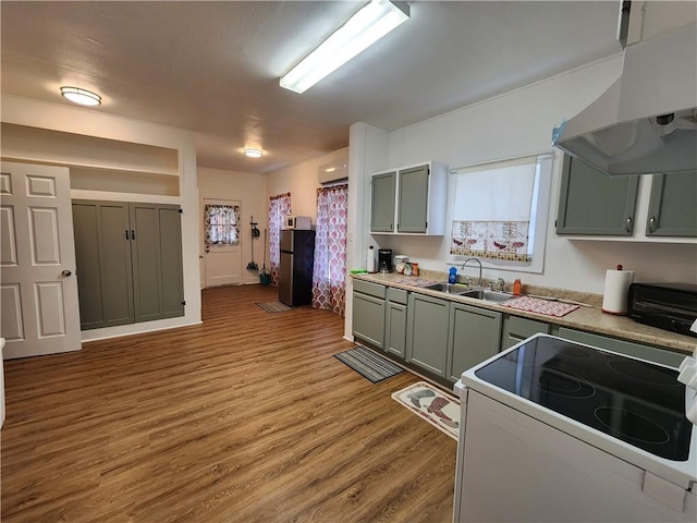 1613 6th St, Corpus Christi, TX 78404 - kitchen featuring white electric range oven, a sink, wall chimney exhaust hood, wood finished floors, and freestanding refrigerator