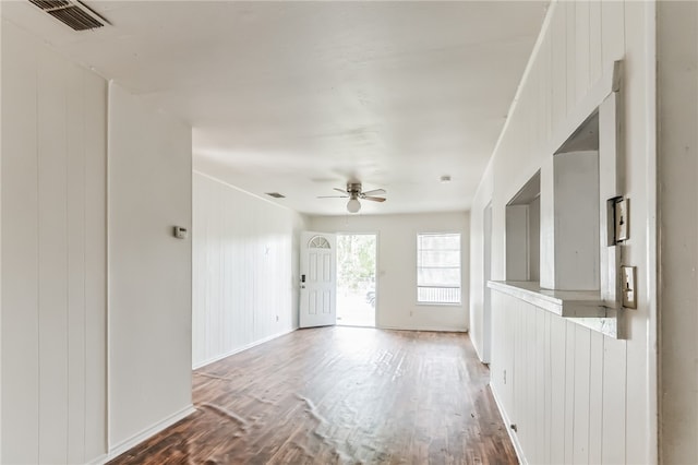 empty room with wood walls, hardwood / wood-style flooring, and ceiling fan