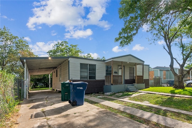 manufactured / mobile home featuring covered porch, a front yard, and a carport