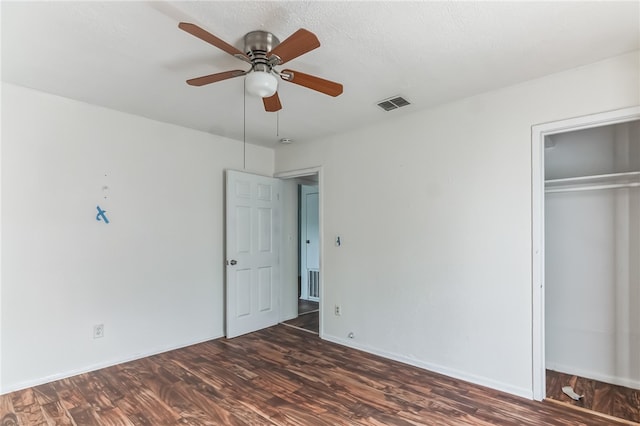 unfurnished bedroom featuring a textured ceiling, ceiling fan, dark hardwood / wood-style floors, and a closet