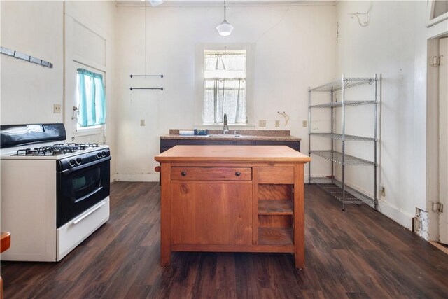 kitchen with dark wood-style floors, gas stove, a sink, hanging light fixtures, and wood counters