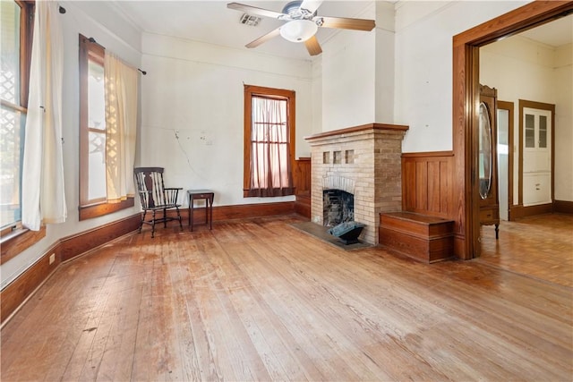 unfurnished living room featuring hardwood / wood-style flooring, a fireplace, visible vents, and ceiling fan