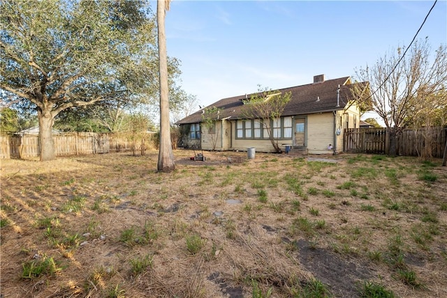 rear view of house featuring entry steps and fence