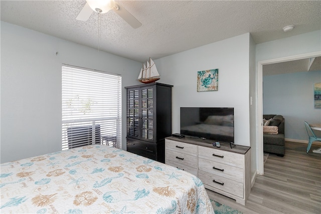 bedroom with ceiling fan, a textured ceiling, and light hardwood / wood-style flooring