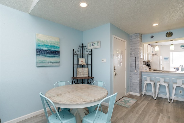 dining area with a textured ceiling and light wood-type flooring