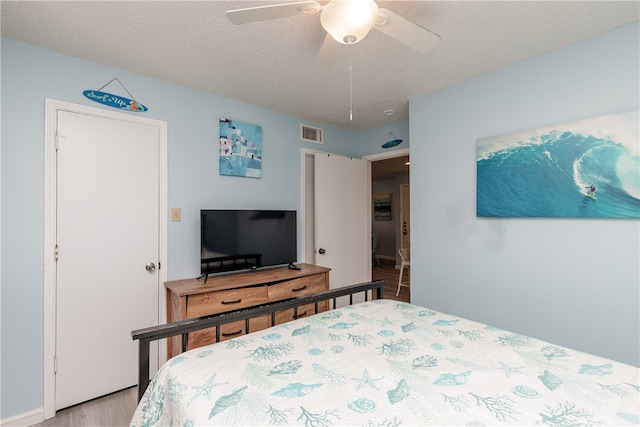 bedroom featuring a textured ceiling, ceiling fan, and light hardwood / wood-style flooring