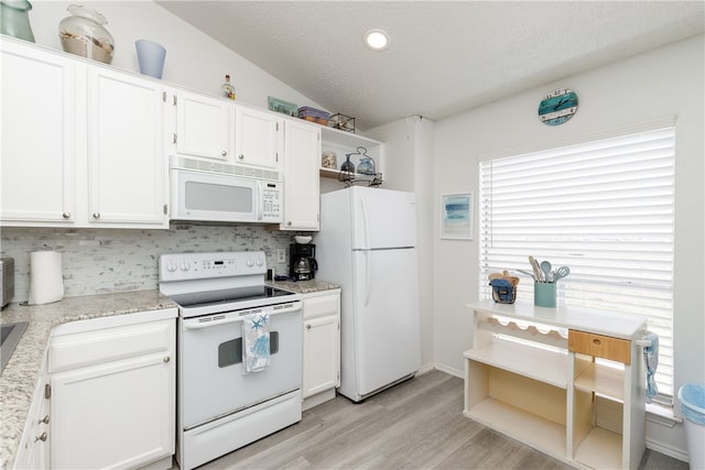 kitchen with white cabinets, light wood-type flooring, lofted ceiling, and white appliances