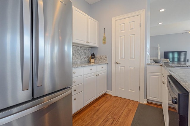 kitchen featuring freestanding refrigerator, white cabinets, dishwasher, light wood-type flooring, and backsplash