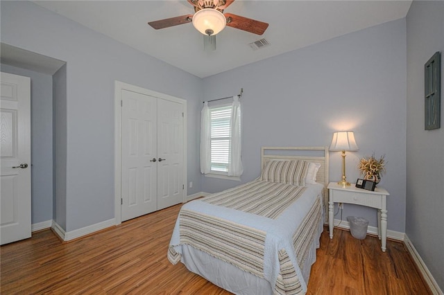 bedroom featuring a closet, visible vents, baseboards, and wood finished floors