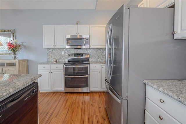 kitchen with light wood-type flooring, tasteful backsplash, appliances with stainless steel finishes, and white cabinetry