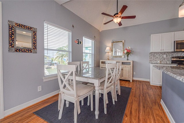 dining room with vaulted ceiling, light wood-style flooring, baseboards, and ceiling fan