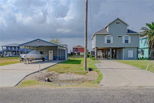 coastal home featuring a carport, a front yard, and a shingled roof