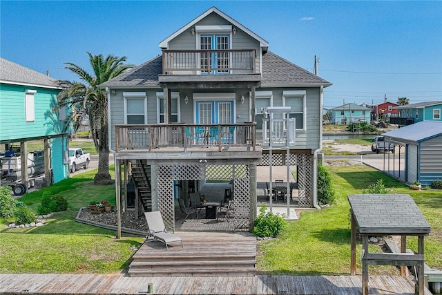 rear view of house featuring a balcony, a lawn, and roof with shingles