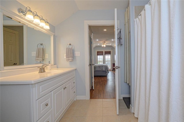 ensuite bathroom with tile patterned flooring, baseboards, lofted ceiling, ensuite bathroom, and vanity