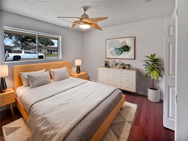 bedroom featuring a textured ceiling, a ceiling fan, and dark wood-style flooring