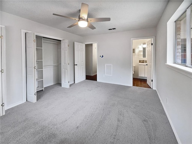 unfurnished bedroom featuring baseboards, visible vents, dark colored carpet, a textured ceiling, and a closet