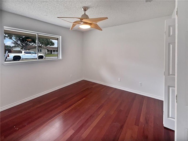 unfurnished room featuring a ceiling fan, a textured ceiling, baseboards, and dark wood-style flooring