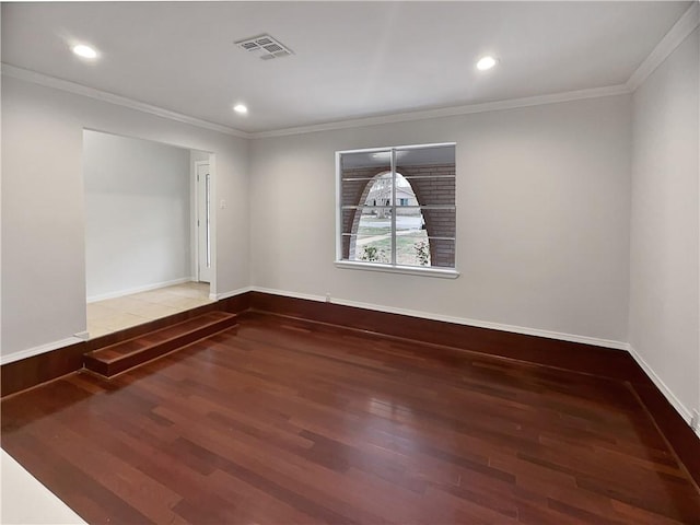 unfurnished room with ornamental molding, wood finished floors, visible vents, and baseboards