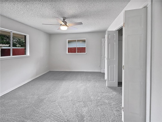 unfurnished bedroom with carpet floors, multiple windows, a textured ceiling, and baseboards