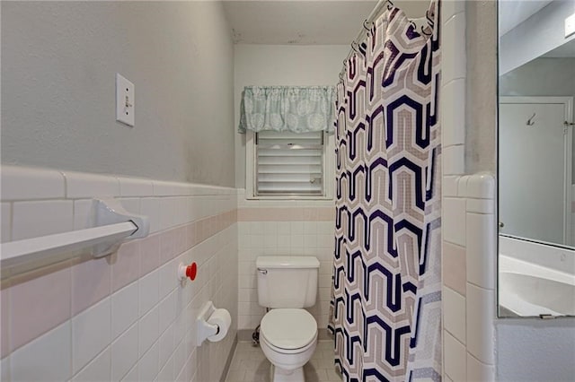 bathroom with a shower with curtain, tile patterned floors, toilet, and tile walls